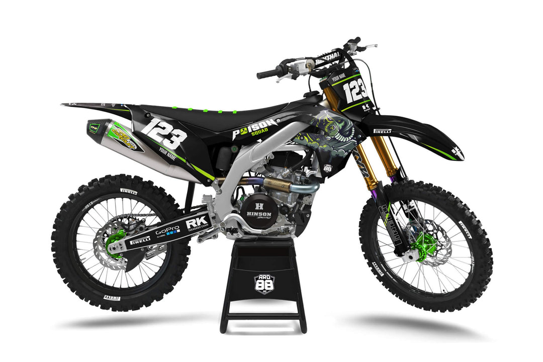 Svart Kawasaki-crosshoj med dekalkit Poison Black – syrligt grönt mot svart och en tecknad varelse i grönt och grått, med vita siffror.