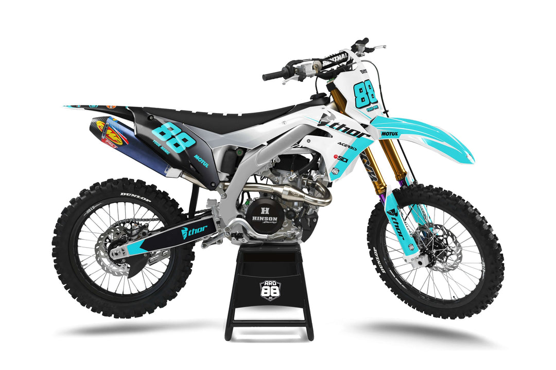 Kawasaki-crosshoj med dekalkitet Transformation Teal: svart bakparti som går över i vitt och silvergrått fram, turkosa detaljer och turkosa siffror 88