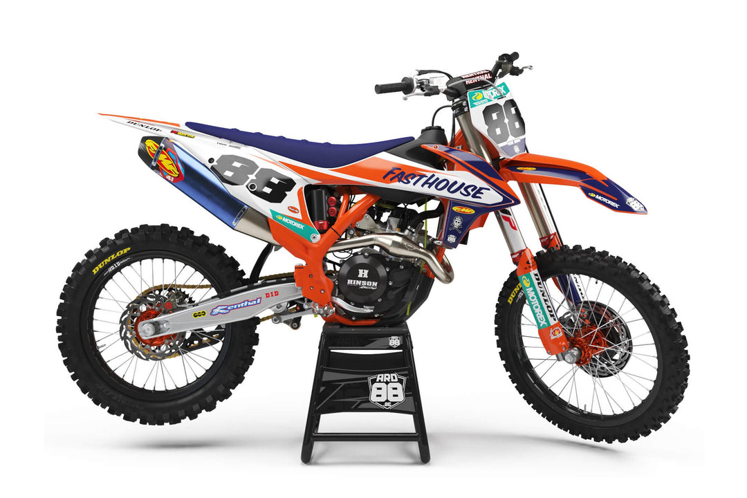 KTM-crosshoj med dekalkitet Fasthouse Blues: vit botten med marinblå fält, orange kanter och svarta startnummer mot vitt.