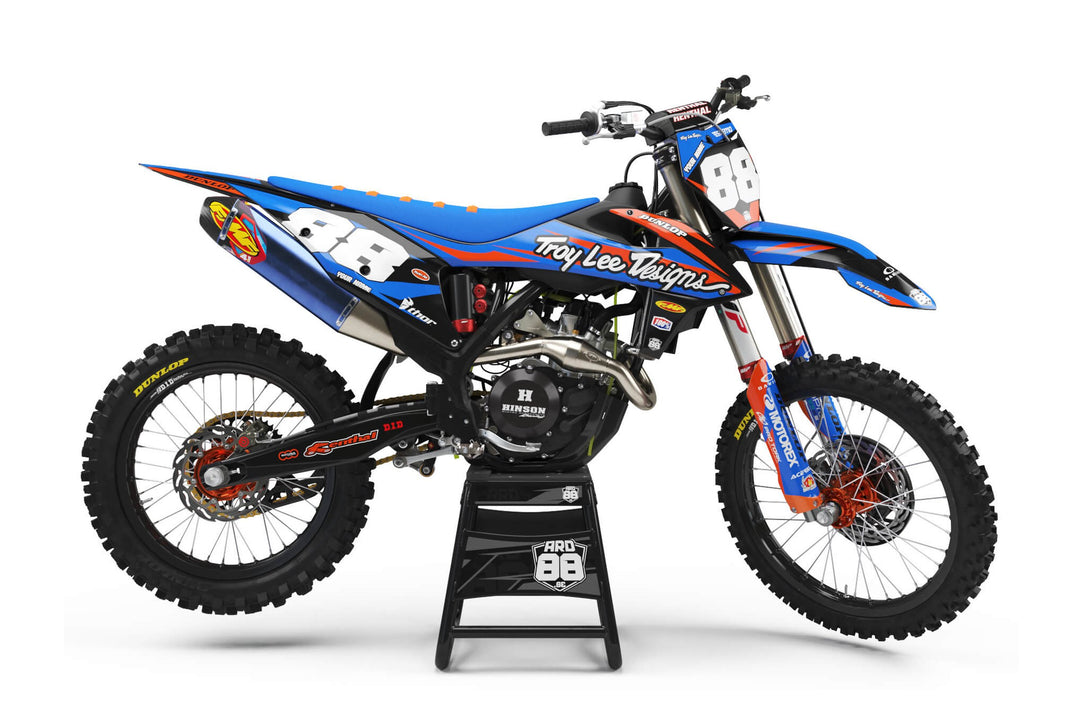 KTM-crosshoj med dekalkitet Mr TLD: blå botten med orange kanter och vita startnummer mot blått.