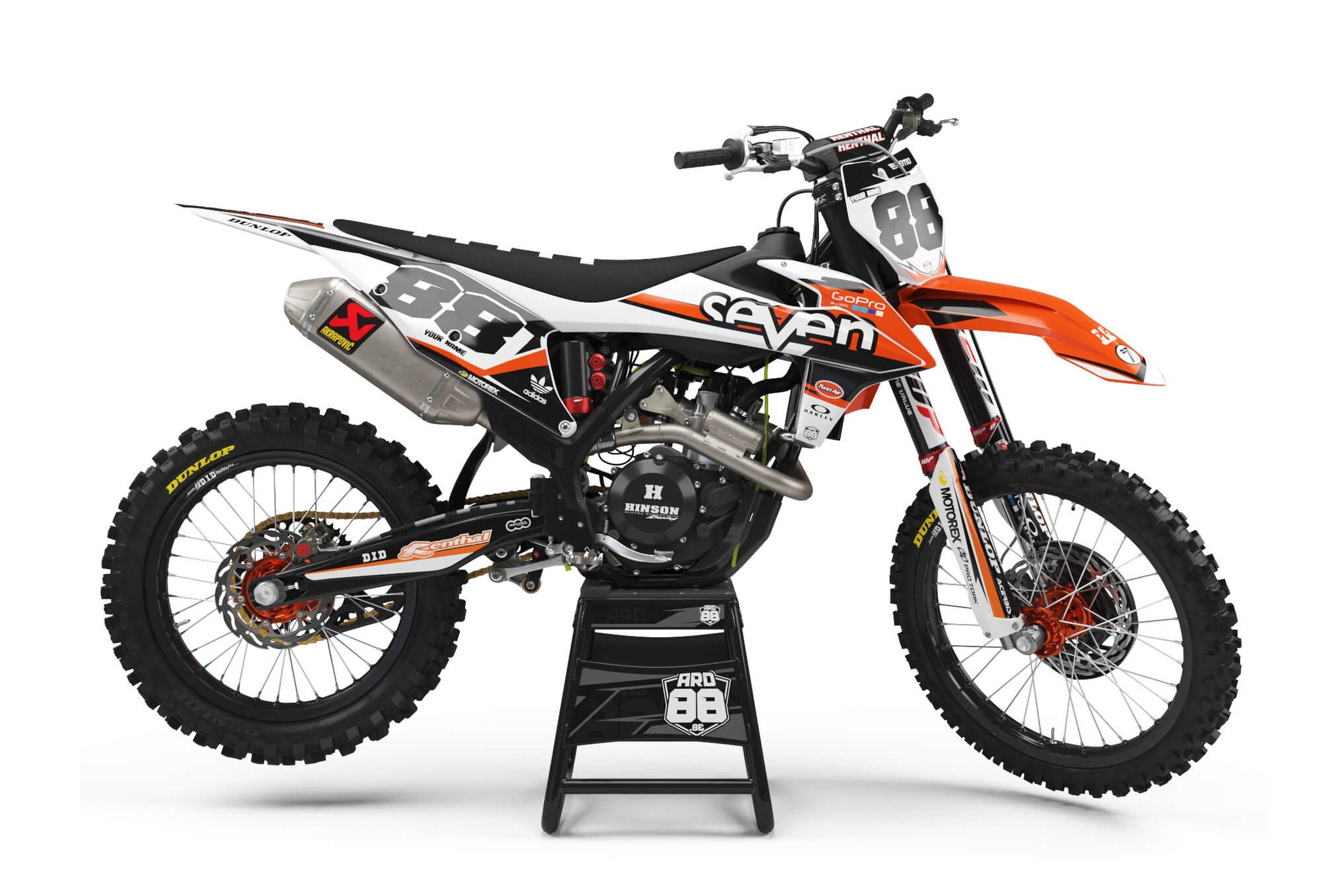 KTM-crosshoj med dekalkitet Seven Oranges – vit och svart grafik med orange accenter och grå siffror mot svart botten