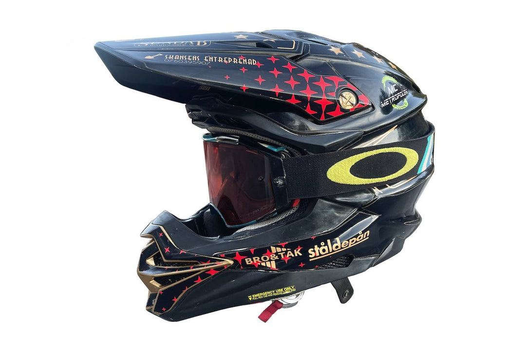 Svart motocrosshjälm med custom hjälmwrap från ARD88, röda stjärnor och guldfärgade linjer